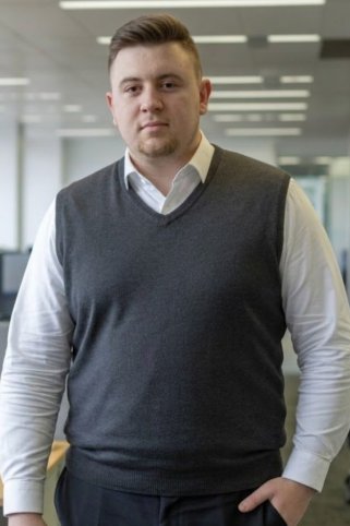 Muž v tmavosivej pletenej veste s V-výstrihom a bielou košeľou, pohľad spredu. Muž v tmavosivej pletenej veste s V-výstrihom a bielou košeľou, pohľad spredu.