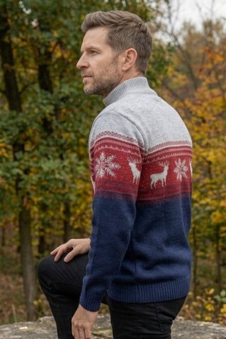 Męski sweter dzianinowy we wzór norweski z jeleniem, z zamkiem pod szyją i w trójkolorowym fasonie, sfotografowany na mężczyźnie w plenerze.