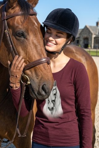 Nasmijana žena u konjaničkoj majici Ewident grli konjsku glavu.